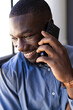 © Wavebreak Media - Smiling African American businessman talking on smartphone near window in office