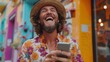 © Atchariya63 - Man in a vibrant floral shirt and hat laughing joyfully while using his smartphone in a colorful urban setting.