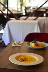 yellow vegetable soup with herbs, squid, pumpkin soup, herbs, plate, serving restaurant table, lunch menu 