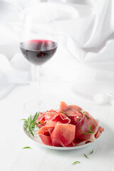 Wall Mural - Prosciutto with rosemary and  red wine on a white wooden table.