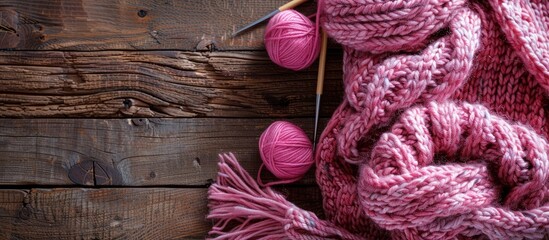 Poster - Horizontal image featuring a knitted item with needles and a pink yarn skein on a wooden backdrop, offering copy space.