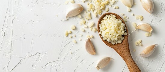 Poster - Wooden ladle with minced garlic on a white desk with a plain background, presenting a top view of the copy space image.