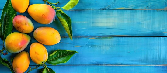 Leinwandbilder - Free copy space image of a mango arranged artistically on a top view of a blue wooden background.