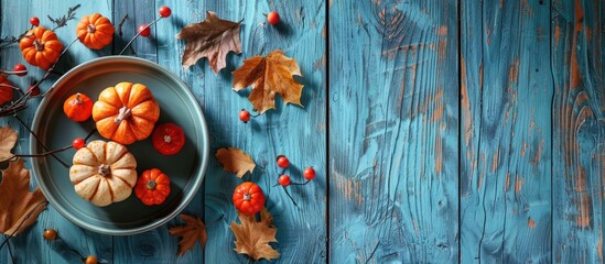 Poster - A plate featuring autumn decorations and pumpkins on a rustic blue wood backdrop with ample copy space image.