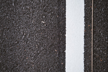 close-up of a freshly painted white line on a black asphalt road, highlighting the texture and contr