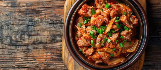Poster - A top view of a ceramic dish with stir-fried pork and kimchi on a wooden table, signaling a homemade food concept with copy space image.