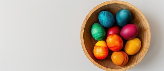 Poster - Closeup of brightly colored Easter eggs arranged in a wooden bowl on a white background with space for adding text or design elements - copy space image.
