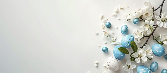 Poster - White Easter concept with decorations on a white background featuring a copy space image. Easter greeting card. Flat lay with an apple tree twig, blue eggs, and a white flower to celebrate the Easter