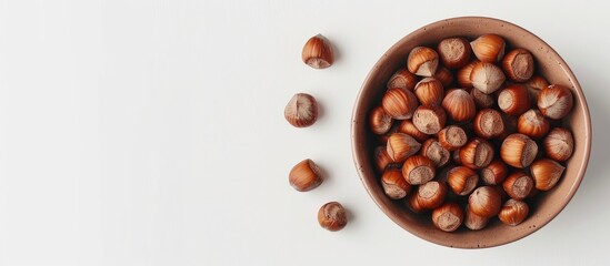 Aufkleber - Overhead view of a bowl filled with hazelnuts on a white backdrop with copy space image.