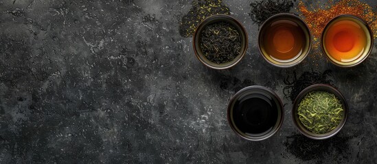 Aufkleber - Four bowls showcasing a variety of tea types, including black and green, set against a textured black stone backdrop with copy space image available.