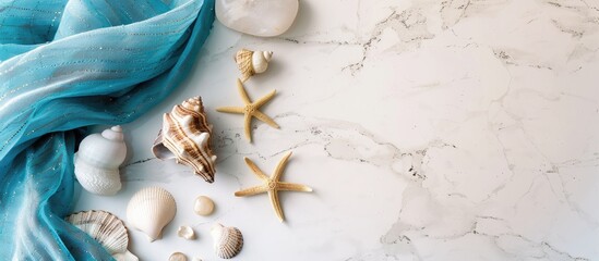 Leinwandbilder - White marble surface decorated with blue fabric, stones, and seashells against a backdrop of the sea, with copy space image.