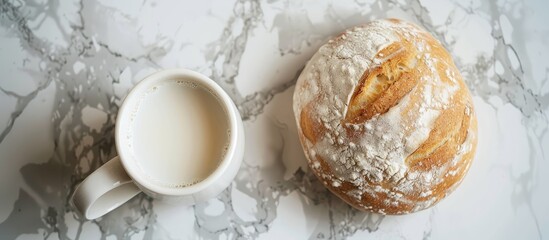 Poster - Top view image showcasing a white round bread placed alongside a mug of milk on a marble surface, with ample copy space available.