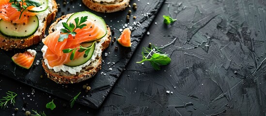 Poster - Top view of delicious salmon, cream cheese, and cucumber toasts on a black table with ample copy space image.