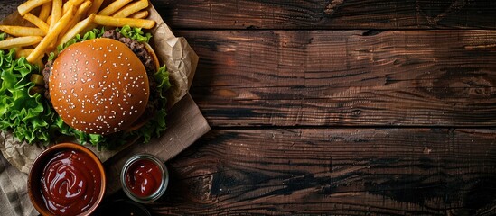 Poster - A homemade burger and fries on a wooden table with a top view, featuring a copy space image.