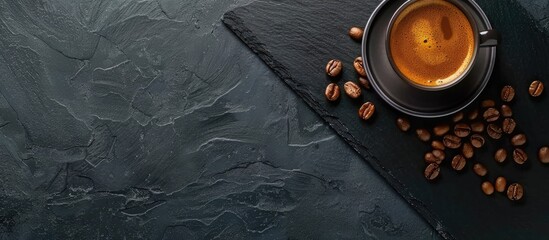 Wall Mural - Top view of a cup of coffee and beans on a black slate stone tray background with copy space image.