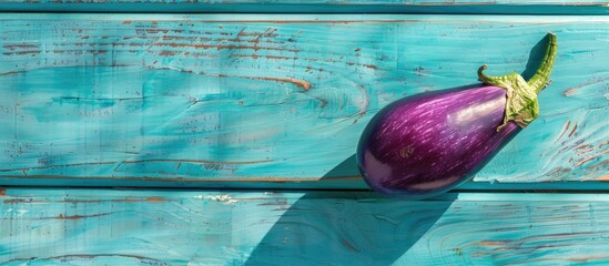 Poster - Eggplant on blue wooden table with shadow, copy space image.