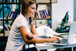 © BullRun - Smiling hipster girl satisfied with useful online language courses watching videos for learning via netbook in college library, positive female student using laptop computer for checking latest news