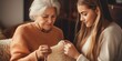 © vefimov - A woman is knitting a sweater while a young woman watches