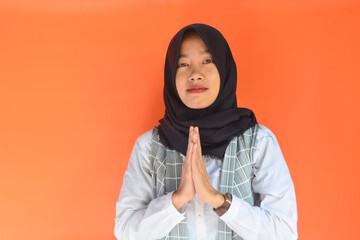 Portrait of a woman gesturing to greet and say hello politely. Isolated orange background