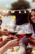 © Xavier Lorenzo - Happy people celebrating summer party toasting with red wine gathered at home terrace.