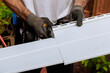 © ungvar - In course of construction, craftsman cuts vinyl siding panels to desired size before installing them