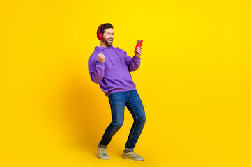 Canvas Print - Full body photo of attractive young man winning headphones hold device dressed stylish violet clothes isolated on yellow color background