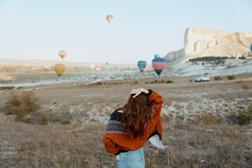 Wall Mural - Spectacular view of woman gazing at colorful hot air balloons in cappadocia, turkey's iconic travel destination