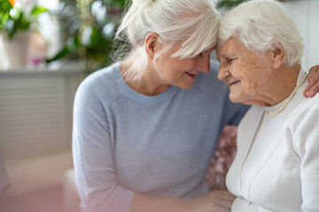 happy senior woman with her adult daughter at home