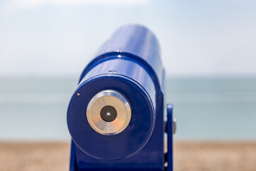 Poster - A close up of a viewing telescope looking out over the ocean, on a sunny summer's day