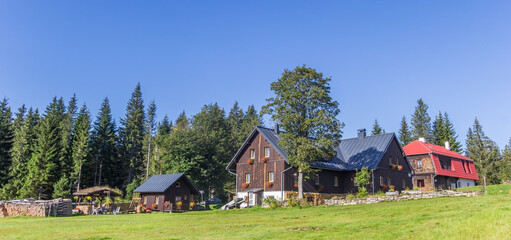 Wall Mural - Panorama of a traditional wooden house in the landscape of the Sumava mountains national park, Czechia