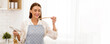 © Prostock-studio - A woman wearing an apron in a kitchen, holding a cooking utensil and tasting food with a spoon.