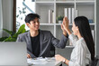 © wichayada - Businessmen Celebrate Success Together at a Meeting with High Five in Modern Office Environment