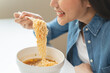 © Pormezz - Young female eating instant noodle isolated on background.