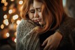© Joaquin Corbalan - Two women with long, red hair embrace each other warmly, standing in front of a background of twinkling Christmas lights.