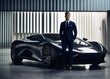 © GS-Studio - A man in a suit is standing next to a black sports car in a modern building.