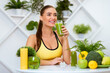 © Prostock-studio - A woman in a yellow sports bra smiles as she drinks a green smoothie in a kitchen setting.