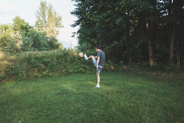 Black-haired athlete plays a friendly football match on the lawn. Amateur sport. Man playing with a ball. Dribbling practice. Sport lifestyle