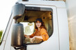 © maxbelchenko - Young woman driving truck. Trucker female worker, transport industry occupation.