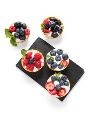 Wall Mural - Board of tasty tartlets with whipped cream and berries on white background