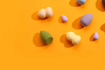Wall Mural - Different makeup sponges on orange background
