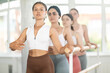 © JackF - Portrait of young girl practicing first position of ballet stance in classical ballet with group of young beautiful girls in sports clothing in light ballet hall