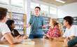 © JackF - Schoolboy talking about his favorite book. Positive teenage students and female teacher discussing in college library