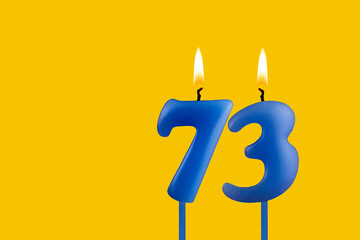 Blue candle number 73 - Birthday on yellow background