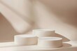 © AgungRikhi - Minimalist product display with three white round podiums on beige background with sunlight.
