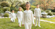 © evgenia_lo - A group of children are wearing white clothing and standing in a grassy area. Scene is peaceful and serene, as the children seem to be enjoying their time outdoors