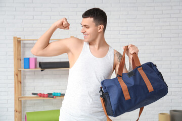 Sticker - Young man with sports bag showing muscles in gym