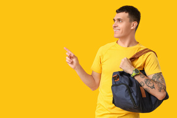 Sticker - Young man with sports bag pointing at something on yellow background