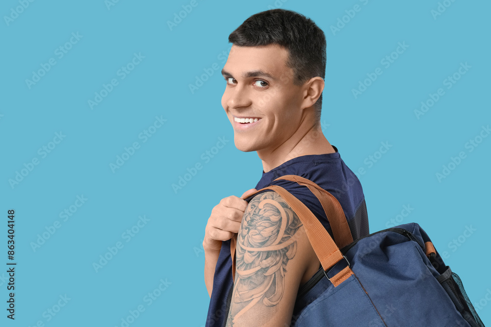 Young man with sports bag on blue background