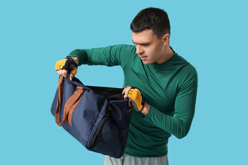 Sticker - Frowning young man with sports bag on blue background