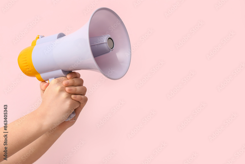 Female hands with megaphone on pink background